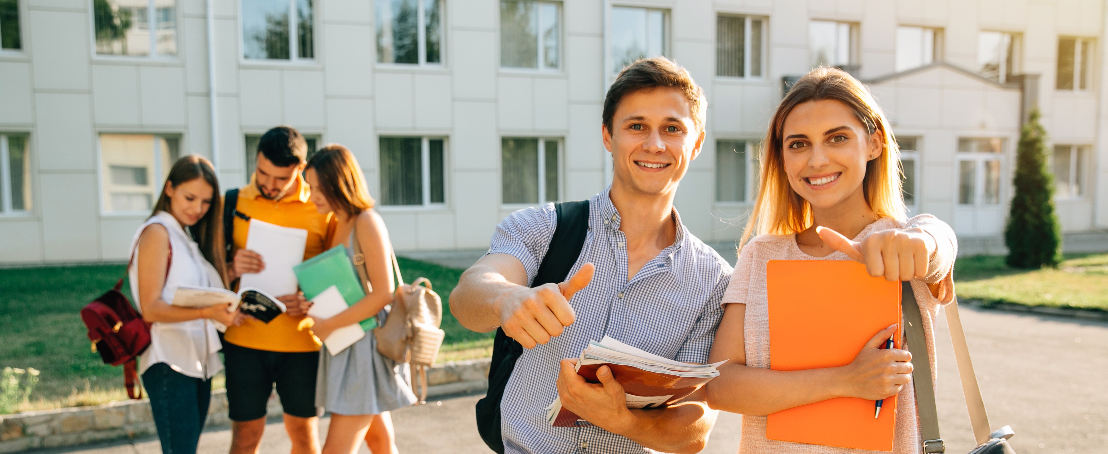 happy-two-young-students-with-note-books-and-backpacks-smiling-and-showing-thumb-up