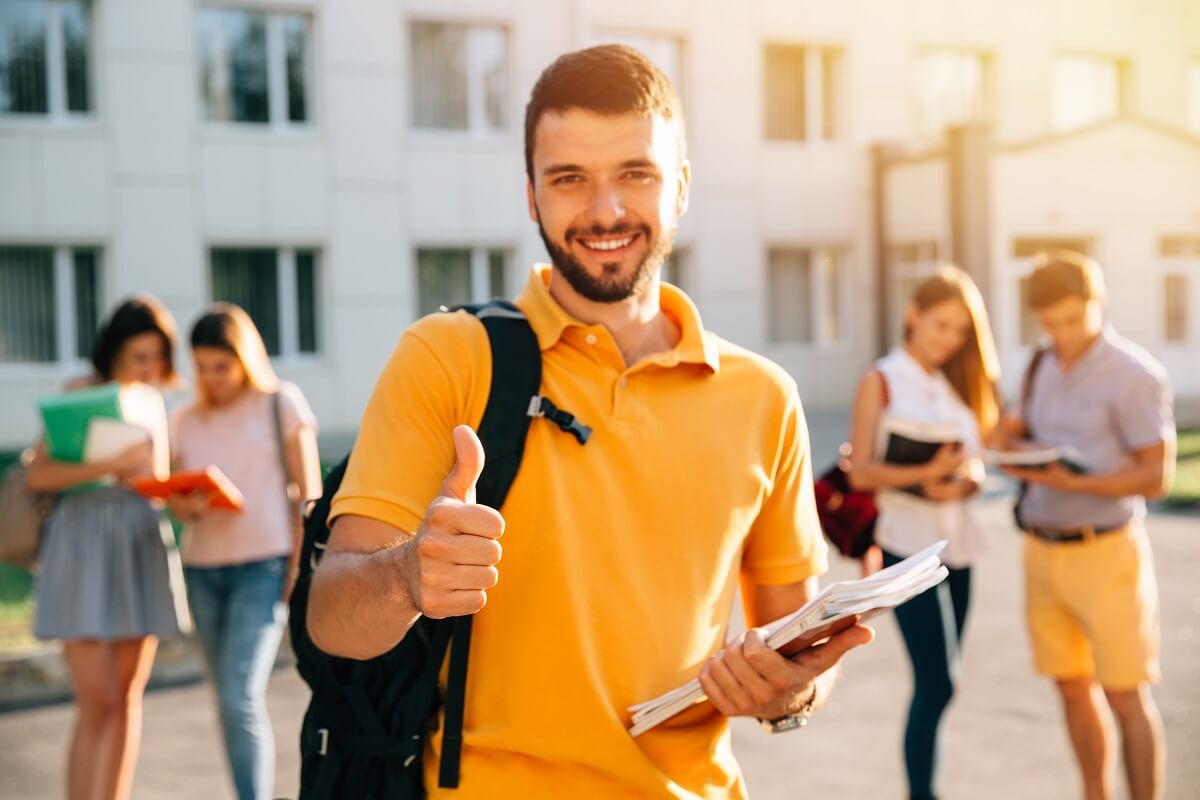 young-attractive-smiling-student-showing-thumb-up-outdoors-on-campus-at-the-university